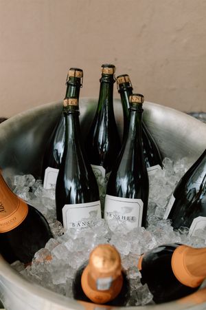 Banshee wine bottles chilling on ice in a large metal bucket at an elegant event.