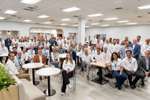 Large group of medical professionals and staff posing together in a modern healthcare facility conference room.