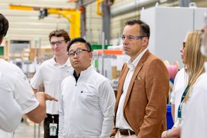 Group of professionals in a factory setting, attentively listening during an industrial facility tour.