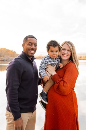 A family shares joyful moments together against a bright autumn backdrop by the water.