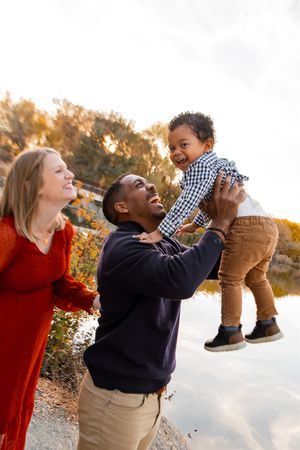Joyful outdoor family photos showing playful lifting and laughing against a sunset backdrop.