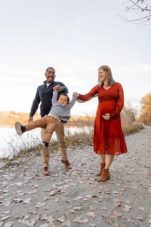 A couple playfully poses in a series of autumn photos on a leaf-covered path during their outdoor photoshoot session.