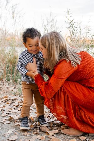 A playful outdoor autumn photoshoot featuring a bright orange dress and checkered shirt among fallen leaves.