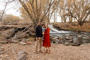 Candid family portrait session along a rocky shoreline during golden hour in autumn.