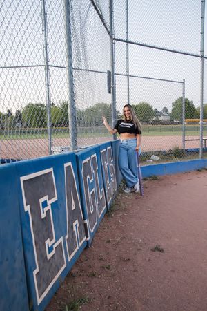 An outdoor portrait by a chain link fence with Eagles team signage visible.