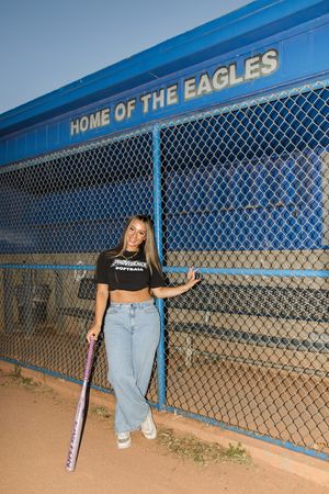 Baseball field with 'Home of the Eagles' sign and chain link fence at sunset.