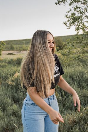 A candid shot in nature wearing a black crop top and light denim jeans.