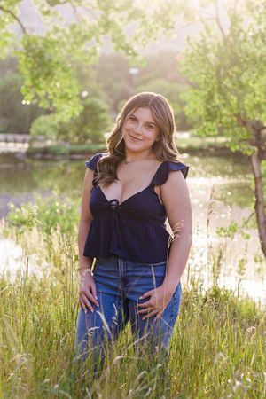 Summer portrait at a tranquil pond with tall grass and sunlit trees in the background during golden hour.