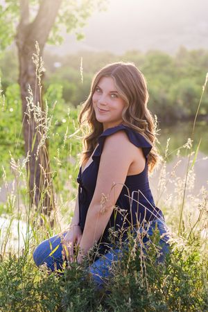 Four outdoor portraits showing a figure in a navy blue top among tall grasses during golden hour sunlight near a lake.