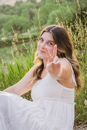A series of photos in a nature setting show someone in a white dress making playful poses among tall grass at sunset.