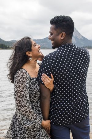 A romantic lakeside moment captured with mountains in the background and coordinated outfits.