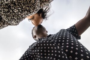 An artistic low-angle shot of a couple in an intimate moment against a bright sky.