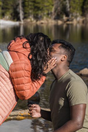 A sweet proposal moment unfolds by a serene mountain lake.