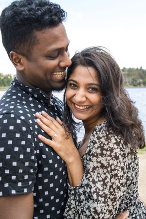 A newly engaged couple sharing joyful moments by a lake.