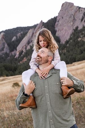 A joyful moment captured in front of the Flatirons rock formation in Boulder, Colorado during golden hour.