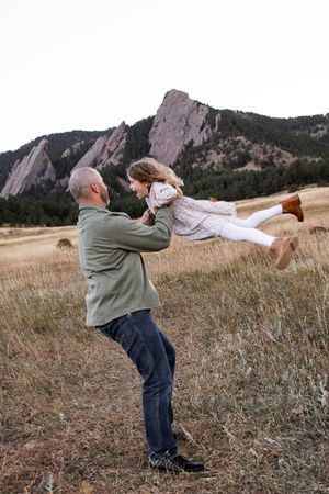 A sequence of four photos showing a person swinging a child in a playful circular motion on a grassy hillside.