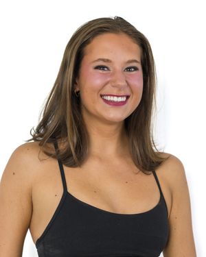 Studio portrait of cheerful athletic woman in black tank top against white background.