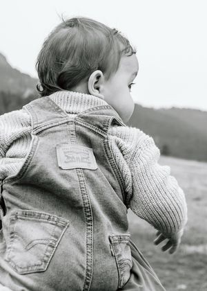 Black and white photo of a toddler wearing a Levi's denim jacket outdoors.