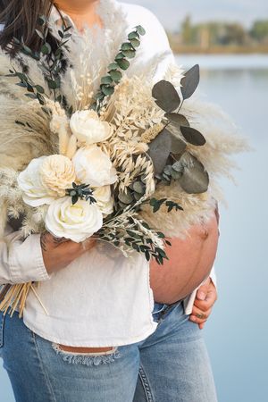 White floral bouquet with dried pampas grass and eucalyptus held against denim in five similar poses.