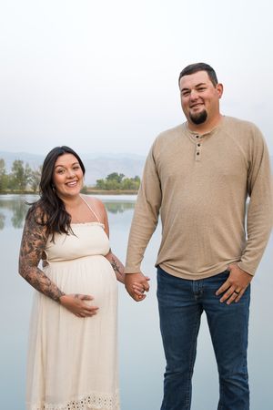 Couple in casual attire poses at a lakeside location, wearing beige and white outfits while showing affection in matching photos.