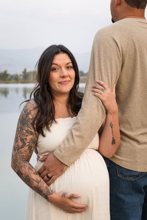 A series of romantic lakeside photos showing a couple embracing, with one person wearing a white top and sleeve tattoos.