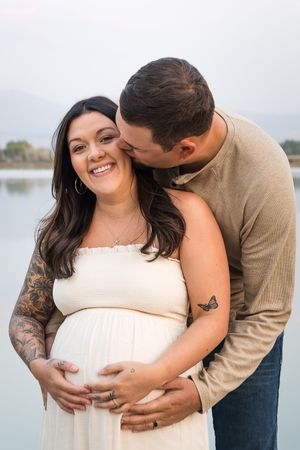 A couple shares intimate moments during an outdoor photo session, with gentle embraces against a scenic waterfront backdrop.