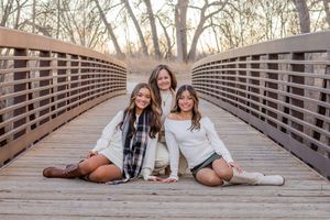 Friends sit and relax together on a rustic wooden bridge walkway during an outdoor photoshoot.