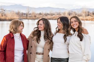 A group of people wearing coordinated winter outfits pose together outdoors in a natural setting.