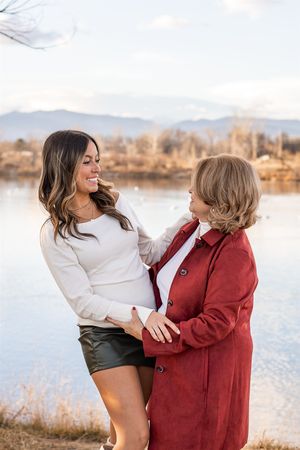 Two people share a joyful moment together by a lake at sunset wearing white and red outfits.