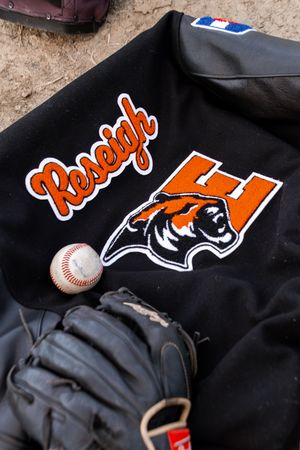 New York Mets baseball jersey logo and baseball on a black uniform fabric background.