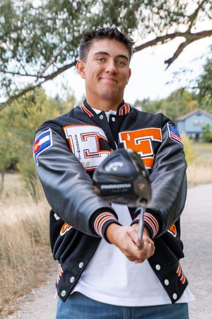 Person in varsity letterman jacket poses for series of casual outdoor portraits with natural background.