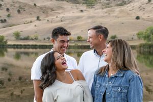 A group of engagement or couple photos taken outdoors near a lake with brown rolling hills in the background.