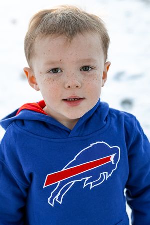 Three Buffalo Bills fans wearing matching royal blue team hoodies with the iconic Bills logo in winter weather.
