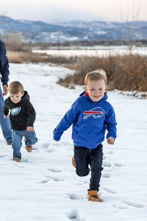 Children running and playing in deep winter snow with mountains visible in the background.