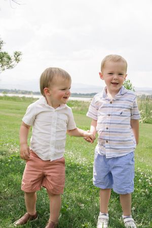 Two toddlers in casual clothes sharing a joyful moment outdoors.