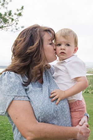 Tender family moment captured outdoors with scenic background.