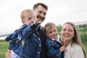 A joyful family wearing matching denim and casual clothes laughs together outdoors.