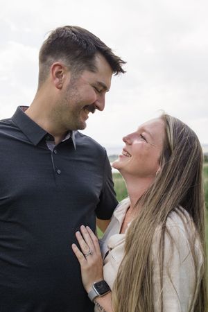 A couple smiles lovingly at each other while embracing outdoors.