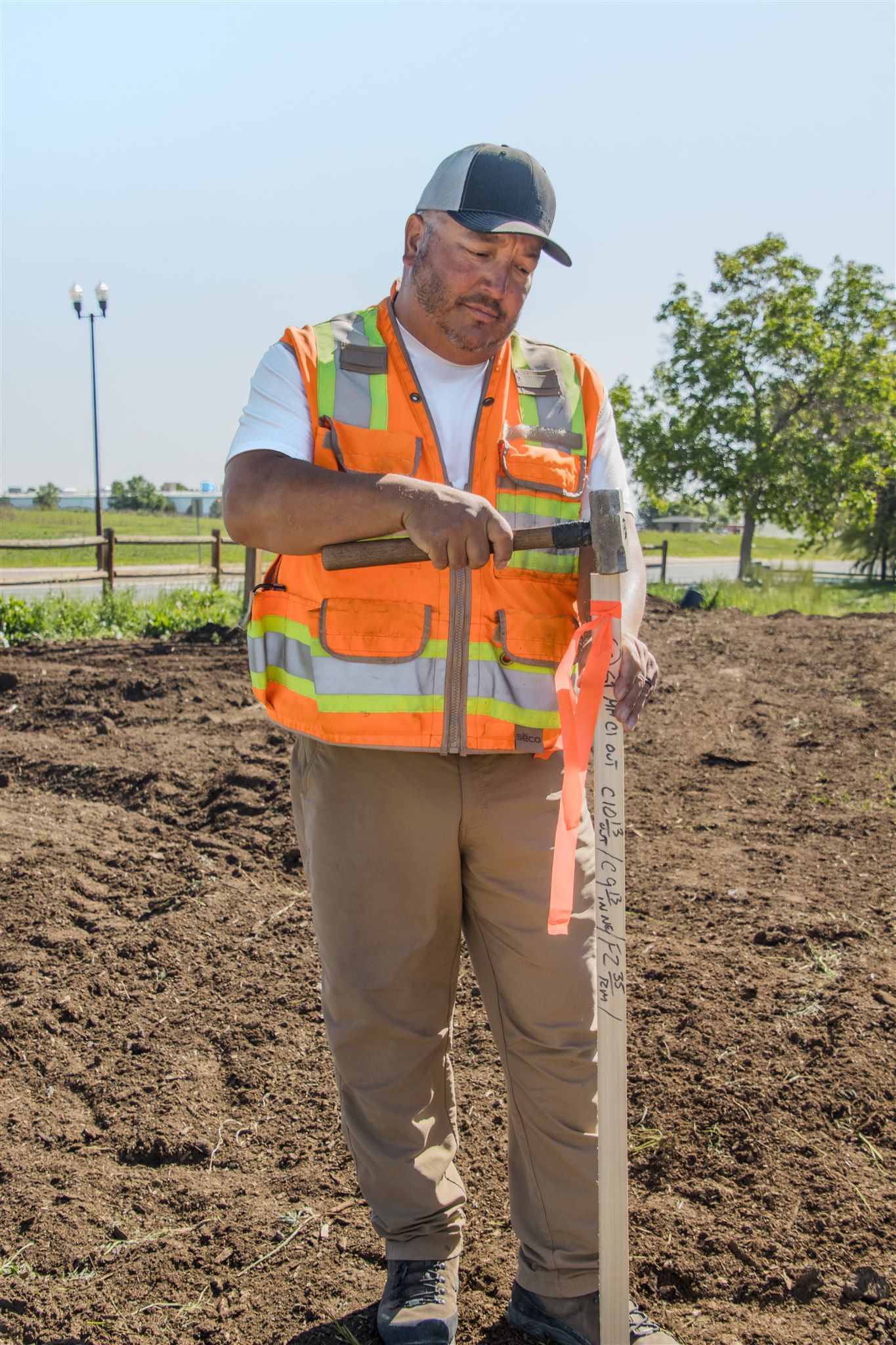 Surveyor in safety gear holding measurement equipment in field.