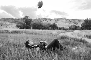 Football flying through the air over a grass field with mountains visible in the distance.