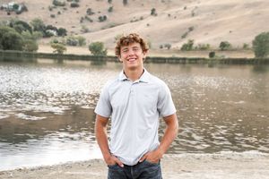 Senior portraits featuring student in casual attire by a scenic lakeside setting.