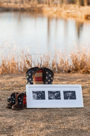 Patriotic American flag boots and framed ultrasound photos displayed near a lake with dried reeds.