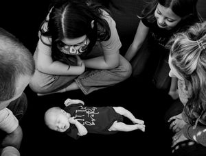 A series of black and white photographs showing hands holding and playing with a small baby.