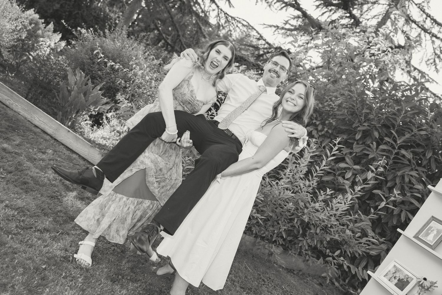 Three people in vintage 1950s style clothing pose together outdoors in a black and white photograph.