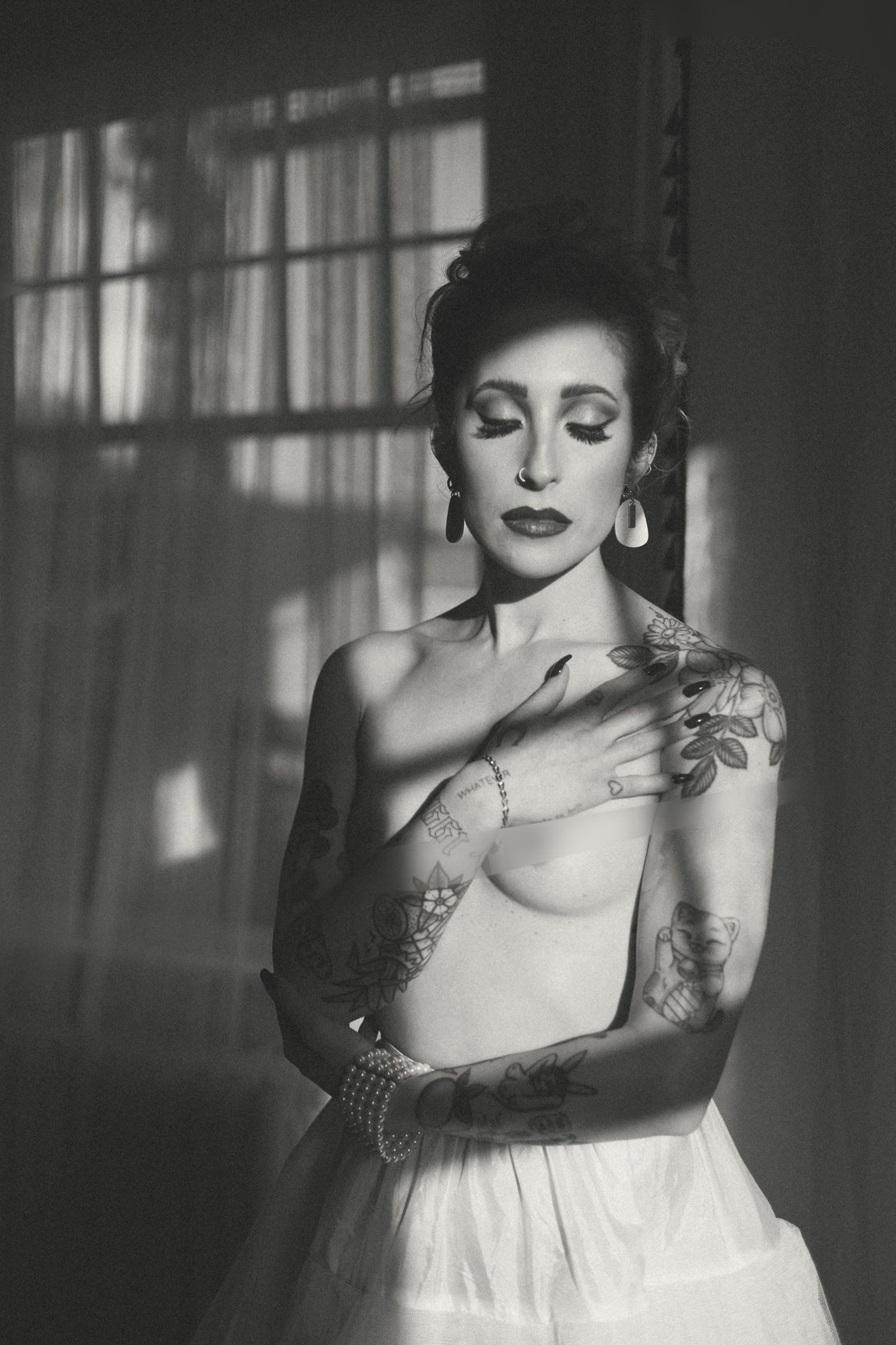 Artistic black and white portrait in dramatic lighting with vintage glamour styling.