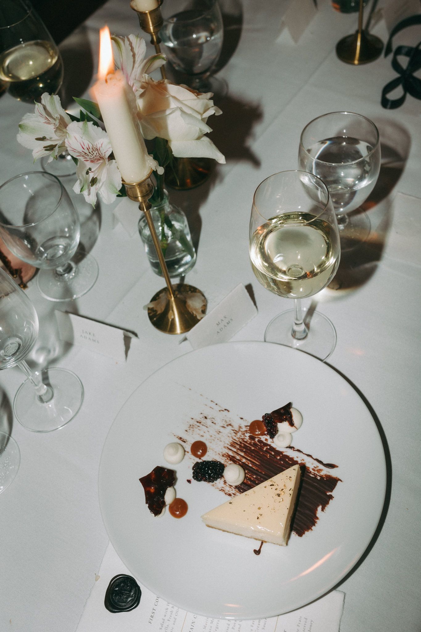 An elegant table setting with wine glasses and dessert plate at a wedding reception.
