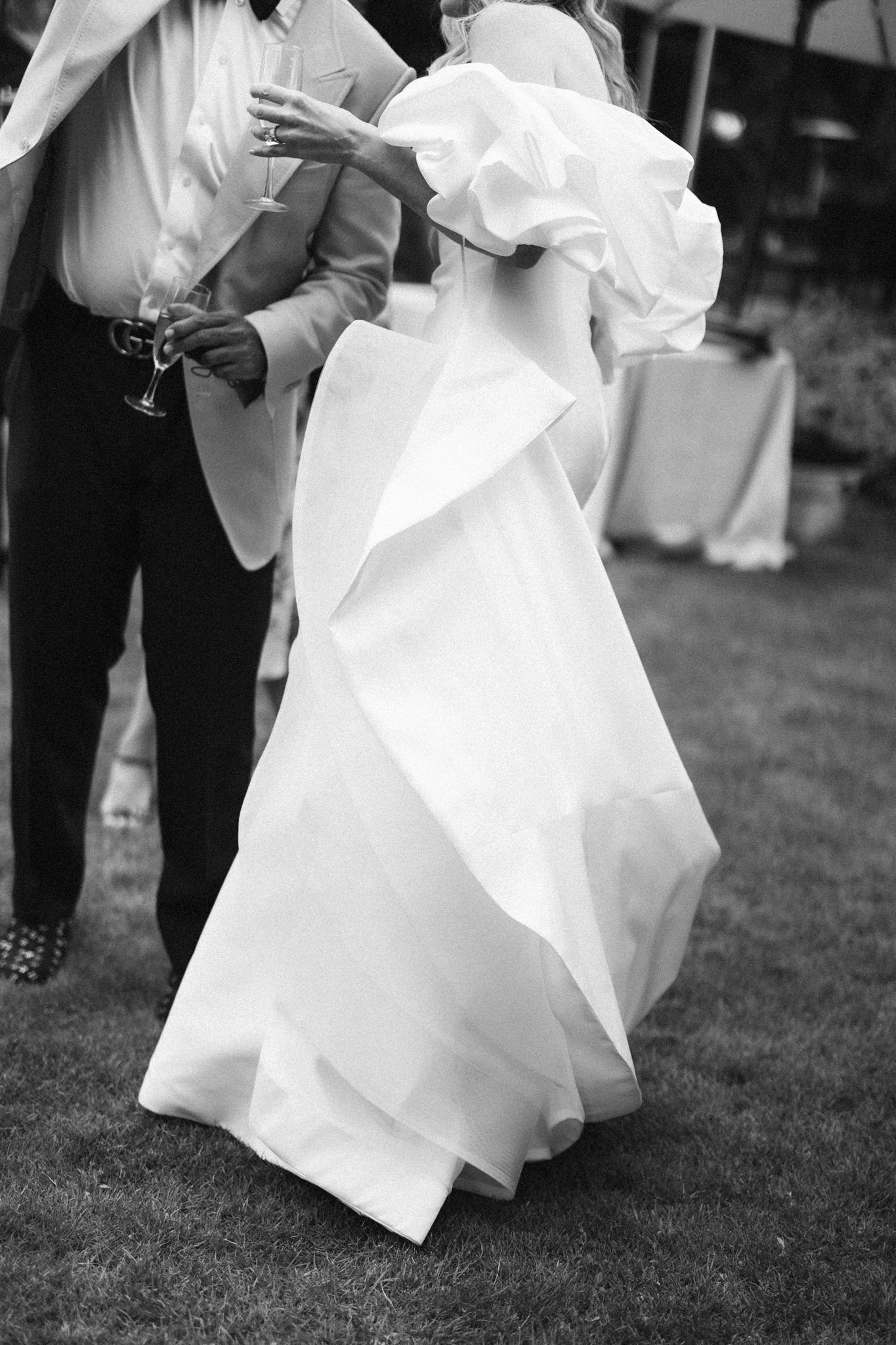 Black and white photo of a flowing white wedding dress moving gracefully across grass.