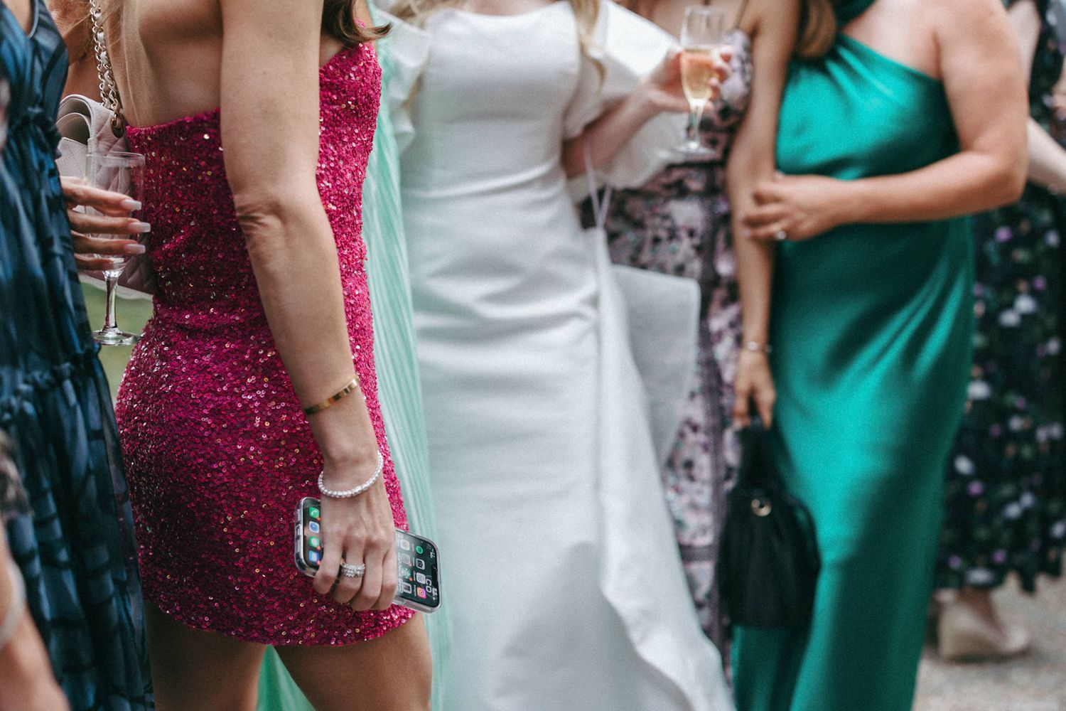 Wedding party wearing jewel-toned dresses in emerald green and burgundy standing together.