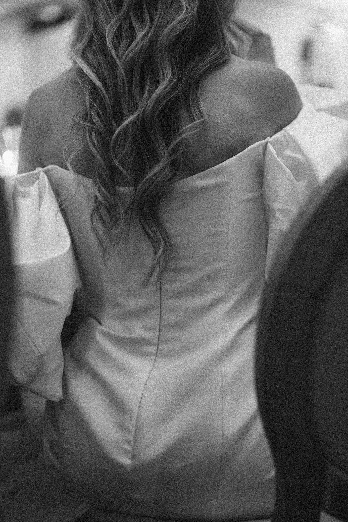 Close-up of a white satin wedding dress detail showing elegant fabric texture and draping.