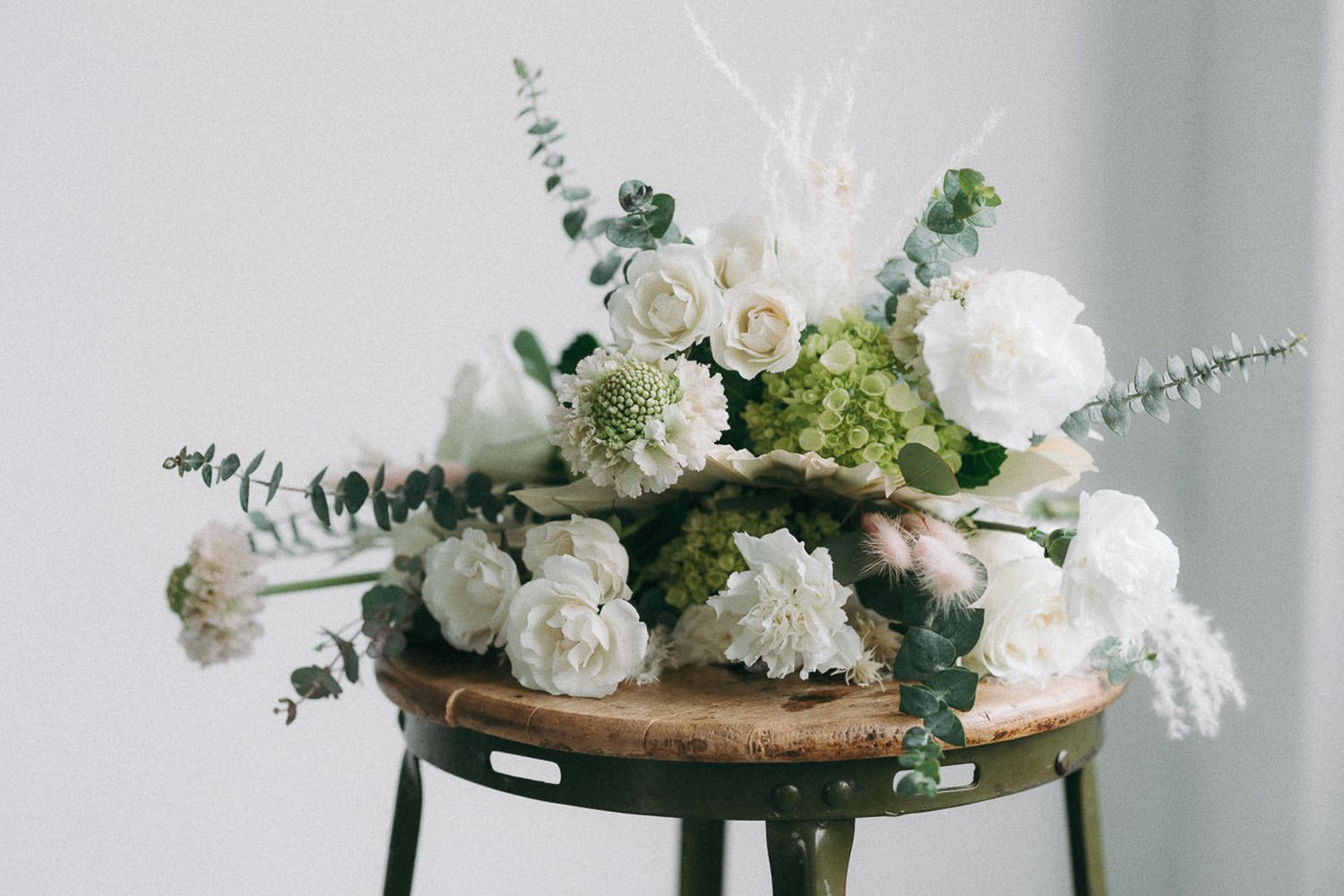 Elegant white floral arrangement with eucalyptus on light background.
